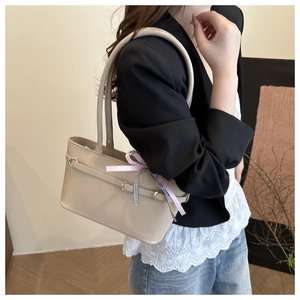 Detail of cream tote bag with decorative pink ribbon bow and silver metal buckle