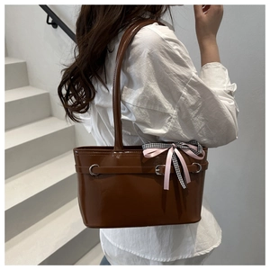 Detail der dunkelbraunen Lackleder-Eimertasche mit dekorativem Band und Metallschnalle
