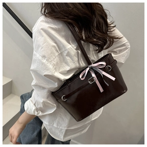 Detail der dunkelbraunen Lackleder-Tasche mit rosa kariertem Seidenband am Schultergurt