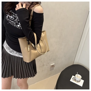Gros plan d'un grand sac cabas beige orné d'un foulard en soie sur la poignée supérieure