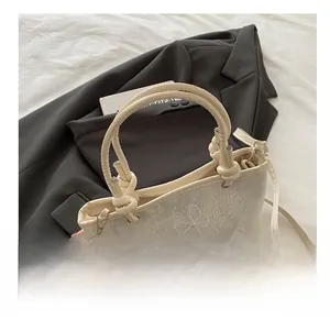 Détail de la broderie en dentelle papillon et de la poignée en corde du sac seau blanc chic