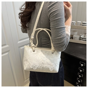 Détail du sac en dentelle blanche avec broderie papillon 3D et bandoulière réglable