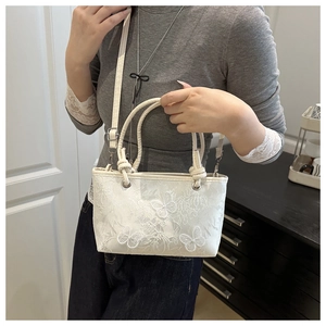 Detail of white lace embroidery handbag featuring 3D butterfly motifs and pearl silk texture