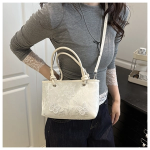 Détail de la broderie de papillon blanc et de la texture jacquard du sac seau