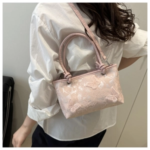 Detail of pink lace bucket bag with 3D butterfly decor worn by a model