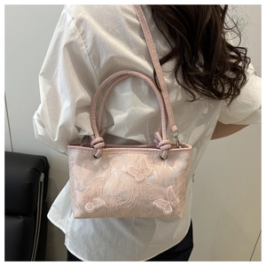 Détail du sac seau en dentelle rose avec des broderies papillon en trois dimensions