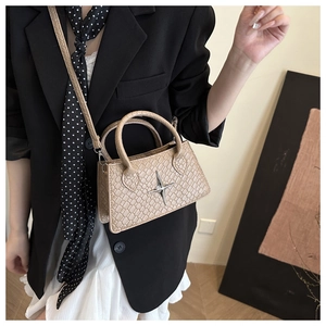 Detail of a beige crocodile pattern square handbag with silver star and slim strap