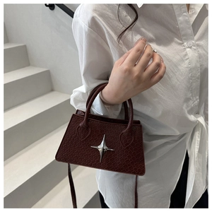 Detail of dark red faux-snakeskin mini bag with silver star ornament on white background