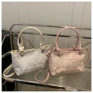 Close-up of floral lace embroidery and 3D butterfly details on small elegant handbags