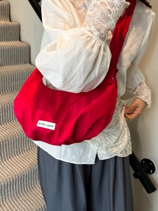 Red croissant crossbody bag made of pleated nylon fabric with Believe in yourself label