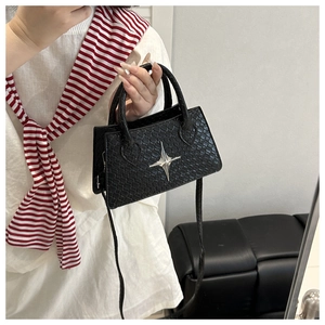 Detail of black mini square bag with crocodile pattern and star shaped metal hardware