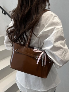 Grand sac cabas en cuir marron avec nœud et boucles porté par un mannequin
