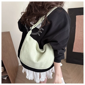 Detail showing the mint green corduroy dumpling bag worn as a shoulder bag on a model