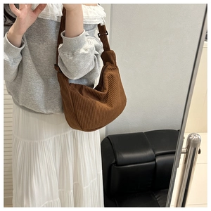 Brown corduroy dumpling bag worn as a shoulder bag in a mirror selfie lifestyle setting