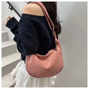 Close-up of pink corduroy dumpling bag worn by model against a minimalist white background