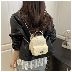 Detail view of mini quilted backpack with metal twist lock and chain strap on model