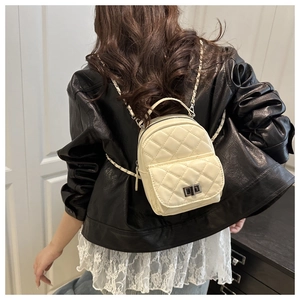 Model wearing a beige quilted mini backpack with silver chain straps and metal twist lock