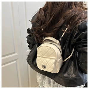 Detail of a mini quilted beige backpack featuring a silver metal lock and chain strap