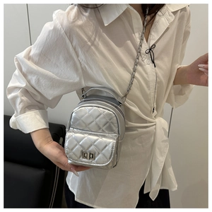 Detail of silver quilted mini backpack with metallic finish and chain strap on model