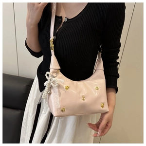 Detailansicht pinke Lacktasche mit goldenen Knochenanhängern und Perlen-Schleifen-Anhänger