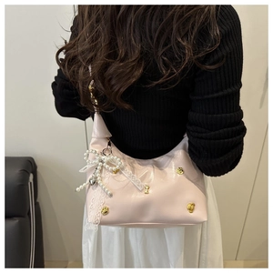 Detail of pink hobo bag with pearl bow, lace ribbons and golden heart studs decoration