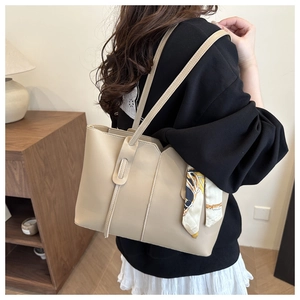 Detailed view of beige tote bag with silk scarf handle and elegant tassel zipper