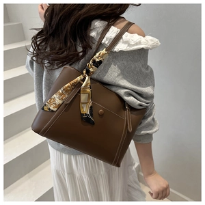 Dettaglio della borsa tote marrone scuro con cuciture a contrasto e sciarpa di seta decorativa