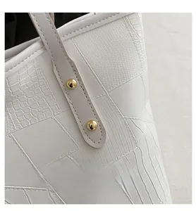 Detail of white tote bag with mixed crocodile and snake skin textures and gold studs