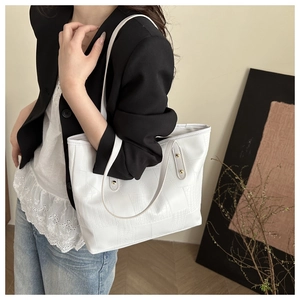 Detail shot of a white tote bag with textured animal pattern and thin shoulder straps