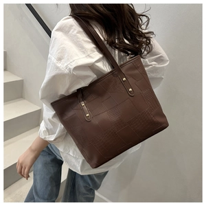 Detail of dark brown tote bag with geometric texture and rivets on shoulder strap