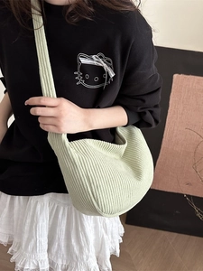 Light green corduroy hobo bag with wide strap worn as a minimalist crossbody bag