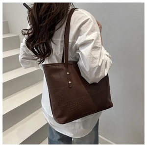 Detail of dark brown tote bag with embossed crocodile and lizard texture stitching