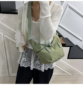 Detail of green dumpling bag featuring rope knot zipper pulls and utility pockets