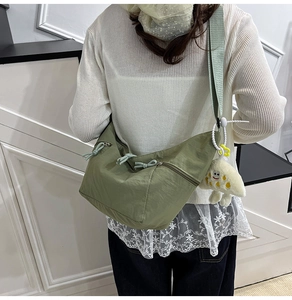 Détail du sac dumpling en nylon vert avec bandoulière réglable et breloque en peluche