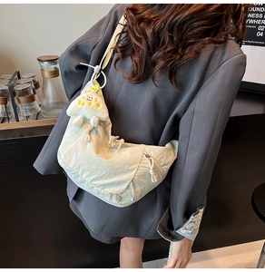 Détail du sac croissant en nylon ivoire avec une breloque nuage portée par un mannequin