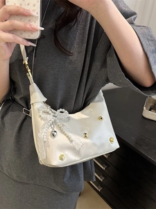 Weiße glänzende PU-Tasche mit Perlen-Schleife und Herzanhänger am Modell präsentiert