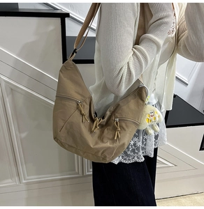 Khaki crescent crossbody bag detail with knotted zippers and cute plush dog pendant