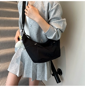 Détail du sac bandoulière croissant noir avec fermeture éclair et charm mouton peluche