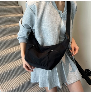 Black crescent moon shoulder bag with front zipper pockets and adjustable wide strap