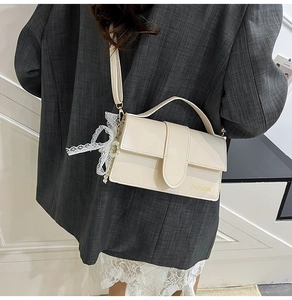 Detail of off-white crossbody bag with lace bow, pearl charm, and FASHION logo