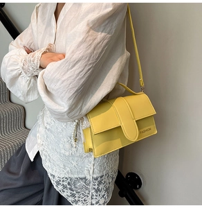 Detail of yellow cross-body bag featuring a wide strap with FASHION text on cover