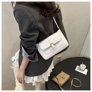 Detail of white crocodile texture crossbody bag with metal buckle on model