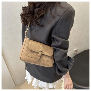 Detail showing the khaki crocodile embossed texture and leather strap on a retro shoulder bag