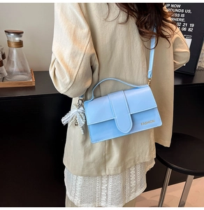 Detail of light blue PU leather shoulder bag with fashion text and lace bow accessory