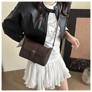 Detailed view of dark brown woven leather texture on a stylish women's shoulder bag