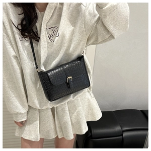 Close-up of black woven PU leather texture and gold buckle on a stylish shoulder bag