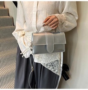 Detail showing a silver textured flap bag with Fashion text and pearl charm accessory