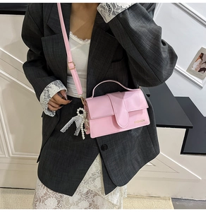 Close-up of pink crossbody bag with gold Fashion lettering and pearl lace charm