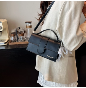 Black leather crossbody bag with fashion gold logo and pearl lace pendant accessory