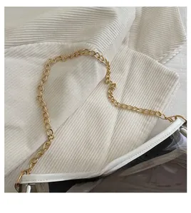 Close-up of golden metal chain strap on transparent PVC bag with white faux leather trim